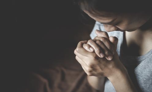 Woman in bed praying as she knows it all starts with prayer and by God's love,mercy, and grace she can rightly set her priorities for the day as she practices discipleship.